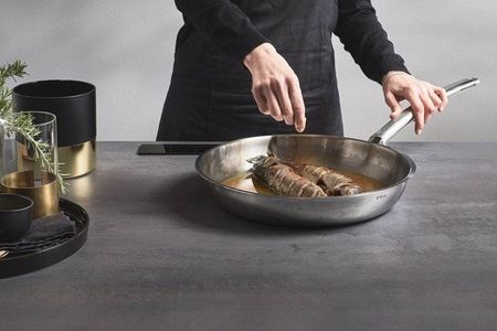 Ein Mann kocht an einer Küchenzeile und bereitet eine Mahlzeit zu.