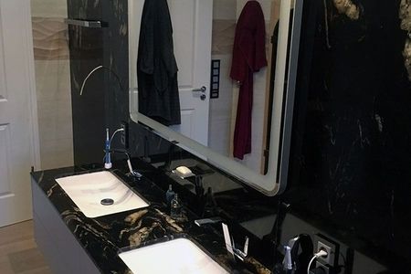 Badezimmer mit schwarzen Marmorwänden und goldenen Akzenten, elegant und modern gestaltet.