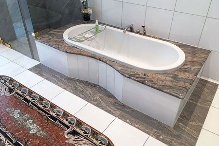 Badezimmer mit einer marmorierten Badewanne und einem großen Teppich auf dem Boden.