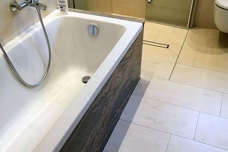 Badezimmer mit einer Badewanne und einer Dusche, ausgestattet mit modernen Armaturen und hellen Fliesen.