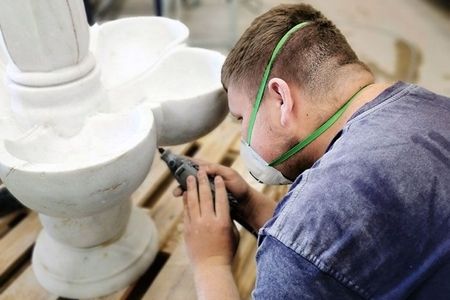 Ein Mann ist mit der Arbeit an einem weißen Marmorfountain beschäftigt.
