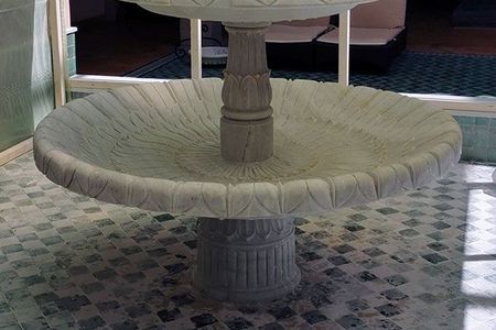 Ein großer weißer Brunnen in einem Raum mit einem großen Fenster im Hintergrund.