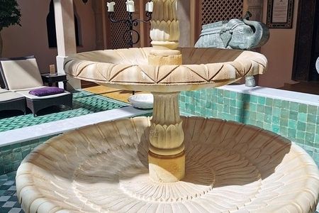 Ein großer Brunnen in einem weitläufigen Raum mit einem Pool im Vordergrund.
